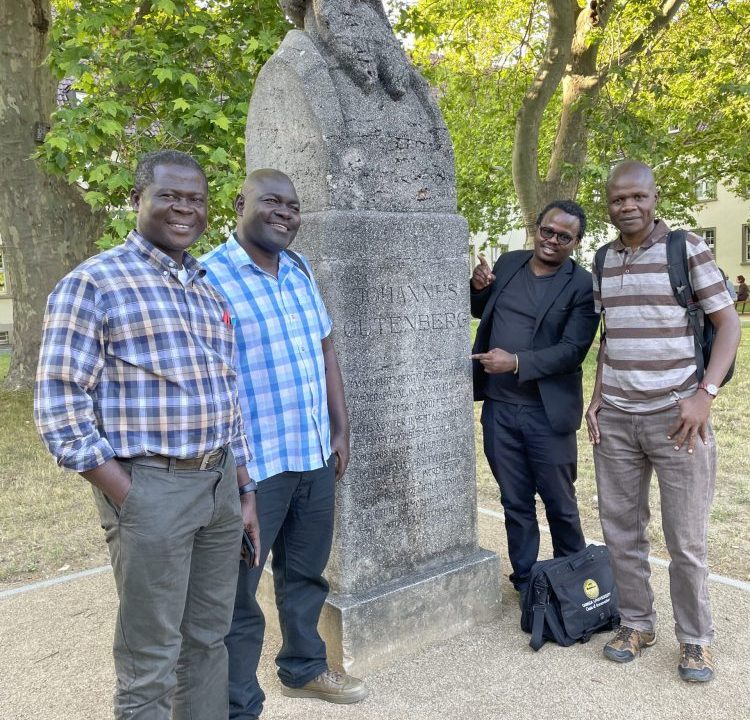 Image taken by Matthias Krings: Patrick Oloko with three Kenyan colleagues in front of the bust of Johannes Gutenberg, at the university campus, Mainz. From left to right: Dr. Patrick Oloko, Dr. James Ogone, Dr. Fredrick Mbogo and Dr. Solomon Waliaula.